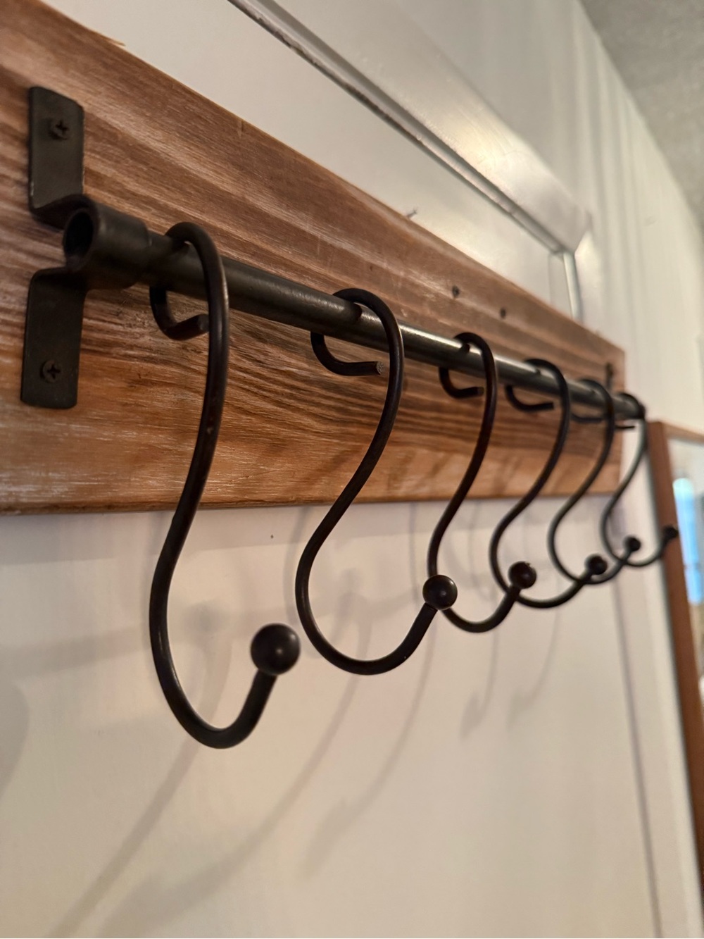 Wall-mounted coat w/6 movable, hand-forged black iron hooks.